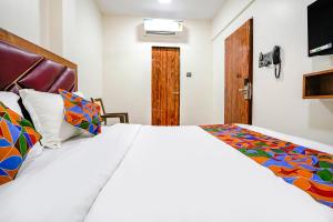 una camera da letto con un grande letto bianco con cuscini colorati di FabExpress Akshay a Mumbai