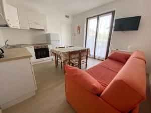 ein Wohnzimmer mit einem orangenen Sofa und einer Küche in der Unterkunft Casa Martinelli in Nago-Torbole
