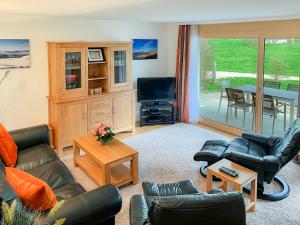 a living room with couches and a television and a table at Chalet Apartments Iseltwald in Iseltwald