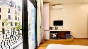 a room with a bed and a balcony with a television at GOLDEN SEA HOTEL *** in Ðố Sơn