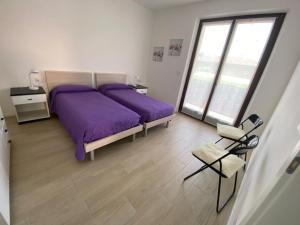 1 Schlafzimmer mit 2 Betten mit lila Bettwäsche und einem Stuhl in der Unterkunft Casa Martinelli in Nago-Torbole