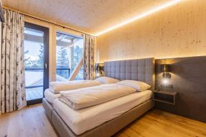 a bedroom with two beds and a large window at Naturchalets Turracher Höhe by ALPS RESORTS in Turracher Hohe