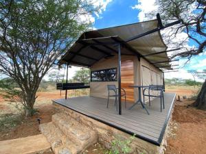 ein kleines Haus mit einem Tisch und Stühlen auf einer Terrasse in der Unterkunft Kameeldoring Glamping Namibia 