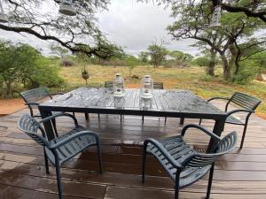 einen schwarzen Tisch mit vier Stühlen auf einer Holzterrasse in der Unterkunft Kameeldoring Glamping Namibia 