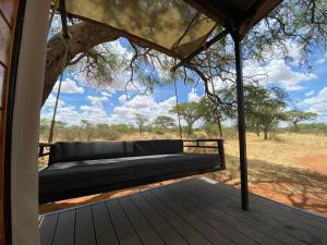 eine schwingende Bank auf einer Veranda mit einem Baum in der Unterkunft Kameeldoring Glamping Namibia 