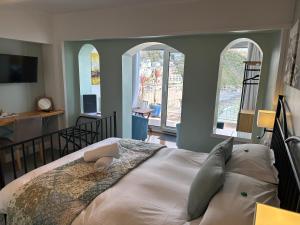 a bedroom with a large bed with two windows at The Watermark in Looe