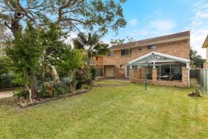 una casa de ladrillo con un toldo y un patio en White Sands Retreat by Experience Jervis Bay, en Vincentia