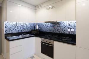 La cuisine est équipée de placards blancs et d'un four avec plaques de cuisson. dans l'établissement 2 BR Condo in Aykon City Tower - Business Bay, à Dubaï
