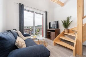 a living room with a blue couch and a large window at Lipno Korzo Residence in Lipno nad Vltavou