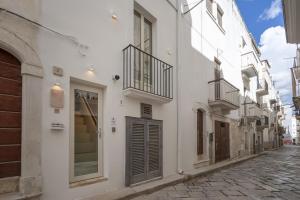 une rue étroite avec des bâtiments blancs et un balcon. dans l'établissement Dimora Giulia, luxury suite and spa, à Castellana Grotte