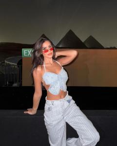 a woman wearing red sunglasses and a crop top and pants at Pyra Hospitality West Pyramids Cairo in Cairo