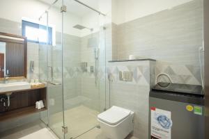 a bathroom with a toilet and a glass shower at Palm Beach Hotel Phú Yên 
