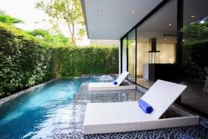 a swimming pool with two white chairs and a house at Greenery Concierge in Mu Si