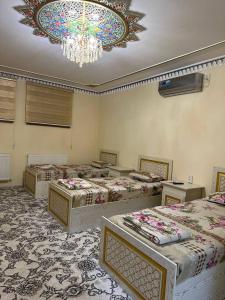 um quarto amplo com 4 camas e um lustre em Faxriddin Guesthouse em Bukhara
