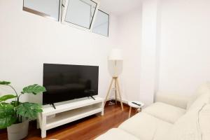 ein Wohnzimmer mit einem Flachbild-TV auf einem weißen Entertainment-Center in der Unterkunft Notel Club - Corazón Urbano in Santander