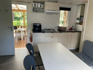 eine Küche mit einem weißen Tisch, Stühlen und einem Tisch in der Unterkunft Mobil home charmant in Argelès-sur-Mer
