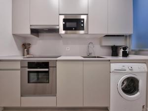 a kitchen with white cabinets and a washing machine at Buen Pastor Cathedral - Iberorent Apartments in San Sebastián