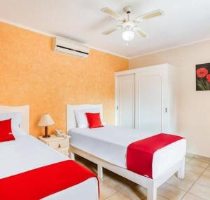 two beds in a bedroom with red and white at Los Anturios in Cuernavaca