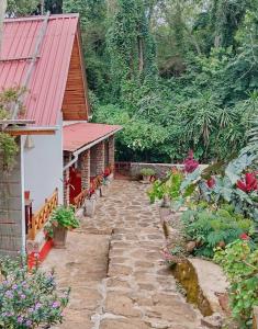 un chemin en pierre menant à une maison avec un toit rouge dans l'établissement Mrefu Eco-lodge, à Marangu