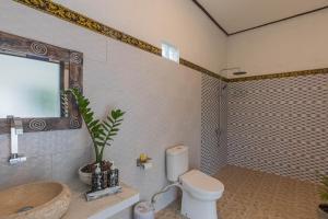 y baño con aseo, lavabo y ducha. en Radjes Bungalow Nusa Penida, en Nusa Penida