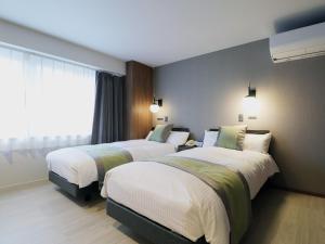 a hotel room with two beds and a window at Hotel Ichibokaku in Yamanouchi