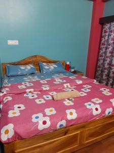 een bed met een roze deken met bloemen erop bij Chewang Homestay in Darjeeling