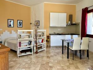 una cucina e una sala da pranzo con tavolo e armadietti bianchi di Il giardino all'angolo a Villacidro