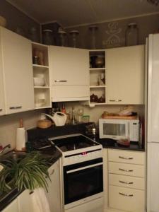 a kitchen with white cabinets and a stove and a microwave at Two room apartment by the lake in Sastamala