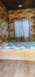 een bed in een houten kamer met een raam bij Tulsi Paradise Resort in Nirmal