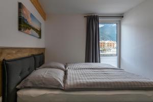 a bed in a bedroom with a large window at Ferienwohnung Klugis in Gosau