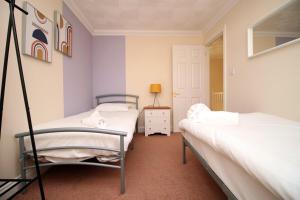 - 2 lits jumeaux dans une chambre aux murs violets dans l'établissement 3 Bed with Free Parking - Merriotts 1 by Tŷ SA, à Newport