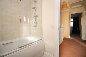 uma casa de banho com um chuveiro e uma banheira branca em 3 Bed with Free Parking - Merriotts 1 by Tŷ SA em Newport