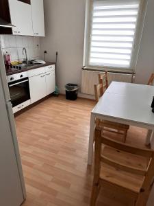 eine Küche mit weißen Schränken sowie einem Tisch und Stühlen in der Unterkunft Domum 7 Ferien- Monteurapartments inkl Wlan und Waschmaschine in Kamen in Kamen