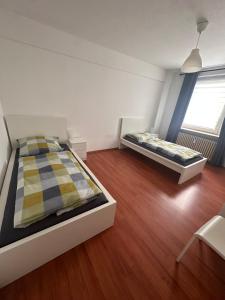 2 Betten in einem kleinen Zimmer mit Holzböden in der Unterkunft Domum 7 Ferien- Monteurapartments inkl Wlan und Waschmaschine in Kamen in Kamen