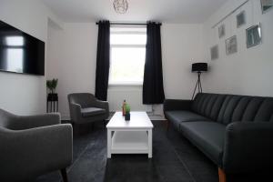 a living room with a couch and a table at 3 Bedroom House in Mountain Ash Cynon View by TŷSA in Quakers Yard