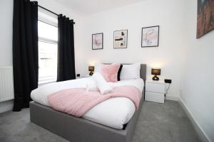 1 dormitorio con 1 cama grande con sábanas rosas y blancas en 3 Bedroom House in Mountain Ash Cynon View by TŷSA en Quakers Yard