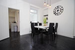 a dining room with a table and chairs and a clock at 3 Bedroom House in Mountain Ash Cynon View by TŷSA in Quakers Yard