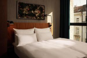 uma cama com almofadas brancas num quarto com uma janela em The Cloud One Prague em Praga