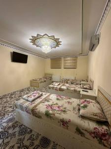 um quarto com três camas e um lustre em Faxriddin Guesthouse em Bukhara
