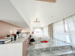 a white room with a bed and a kitchen at Casapapa Home&Space in Talat Amphoe Nakhon Chai Si