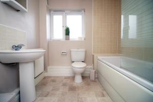 a bathroom with a toilet and a sink and a tub at Alicia's House by Tŷ SA in Newport