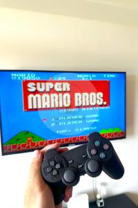 a person holding a video game controller in front of a tv at Twin Lakes Tagaytay - Cozy Staycation with Sglobal in Laurel +17 photos