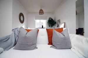 a white couch with orange and gray pillows at Alicia's House by Tŷ SA in Newport