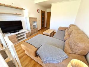 uma sala de estar com um sofá e uma televisão de ecrã plano em Apartamento Playa Foz em Foz