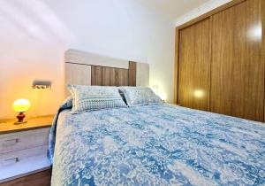 um quarto com uma cama azul e uma cabeceira em madeira em Apartamento Playa Foz em Foz