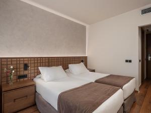a bedroom with a large bed with white sheets at Civitel Akali Hotel in Chania