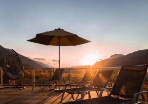 a deck with chairs and an umbrella at sunset at Hotel Samerhof in Tröpolach