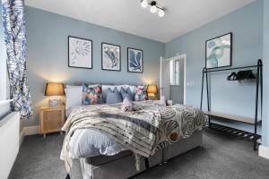 um quarto com uma cama grande e paredes azuis em 4-BR Chic Spacious House with Parking, Central Bolton, Links to Manchester, Sleeps - 11 by Blue Puffin Stays em Farnworth