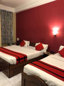 two beds in a hotel room with red walls at HOTEL BREEZE NEW JALPAIGURI in Siliguri