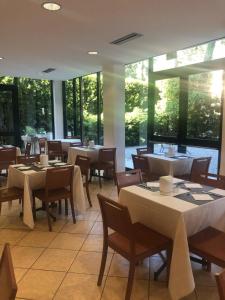 ein Restaurant mit Tischen und Stühlen und großen Fenstern in der Unterkunft Des Bains 138 B&B in Milano Marittima